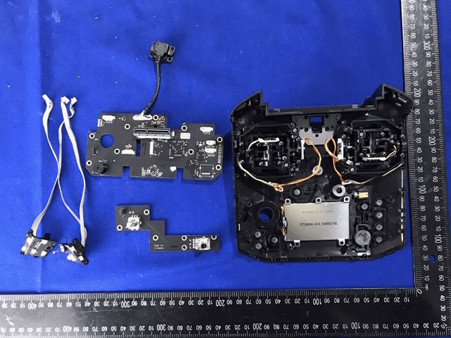 Controller interior with joystick gimbals, shielded ICs, and multi-layer PCB layout.
