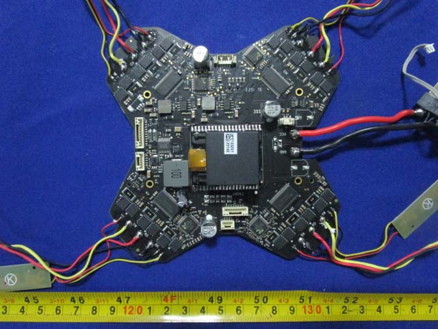 X-shaped flight controller/power board with dense central IC population.